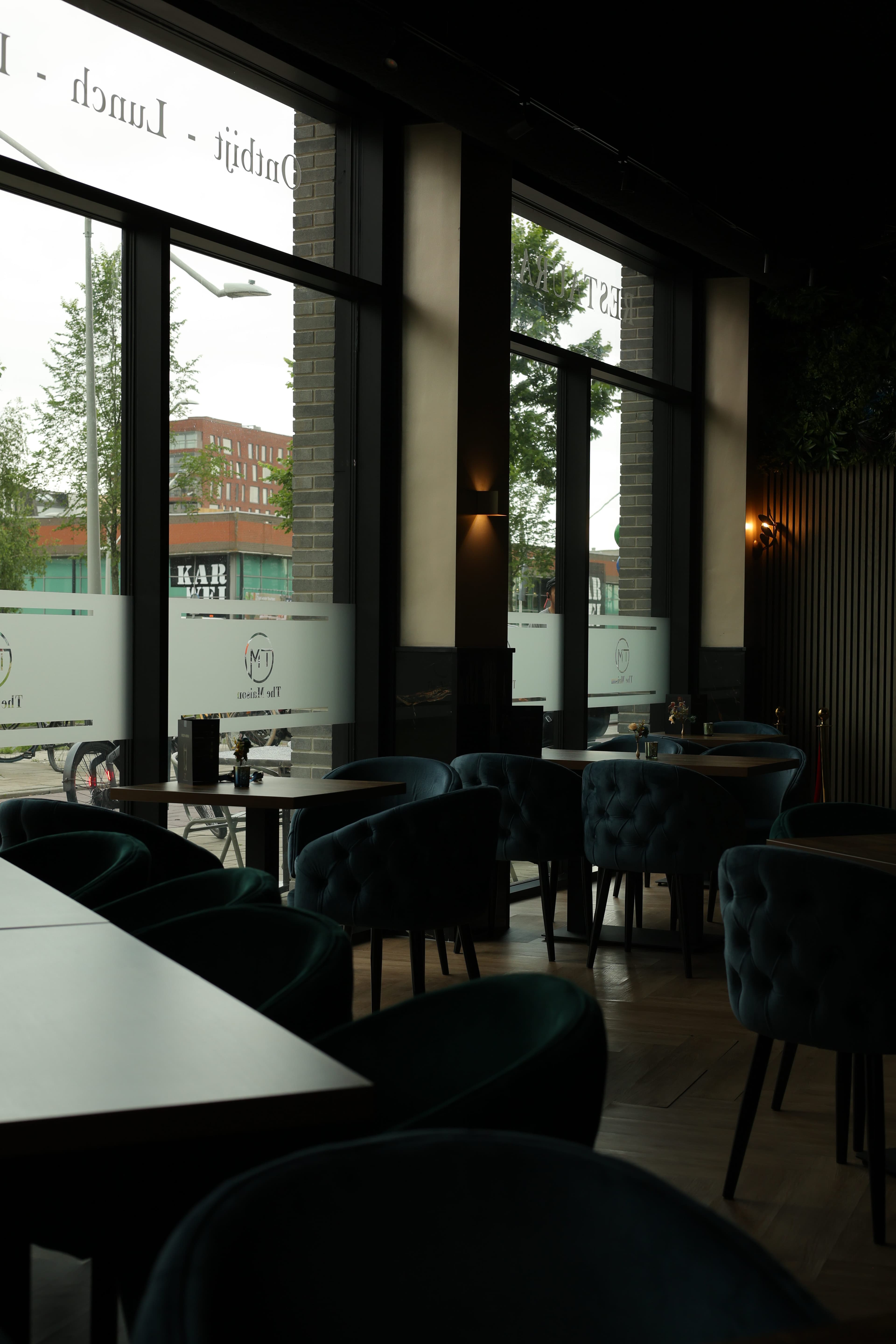 Raampartij met fluwelen stoelen en uitzicht op Amsterdam-Noord