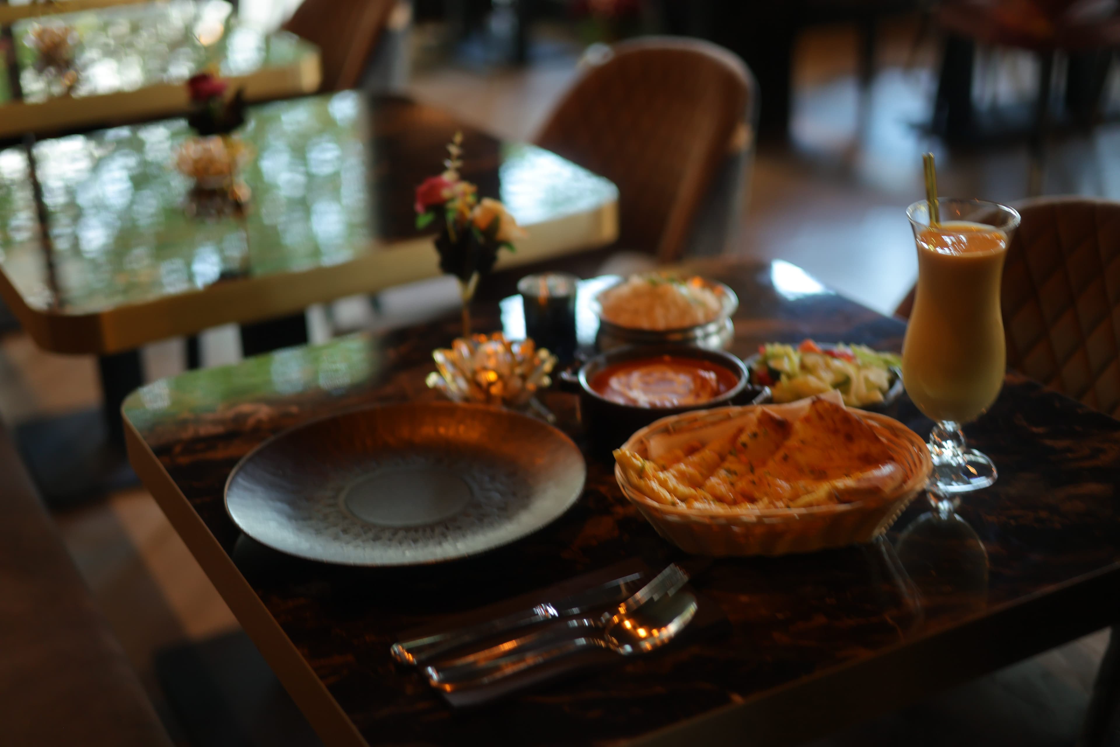 Curry in koperen pan met bijgerechten en kruiden bij The Tandoor Company Amsterdam